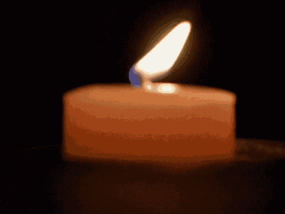 a candle is lit up in the dark and has a blue flame