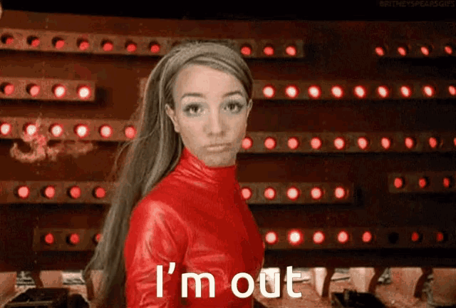 a woman in a red jacket says i 'm out in front of a wall of red lights