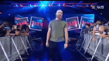 a man in a green shirt is walking into a wrestling arena