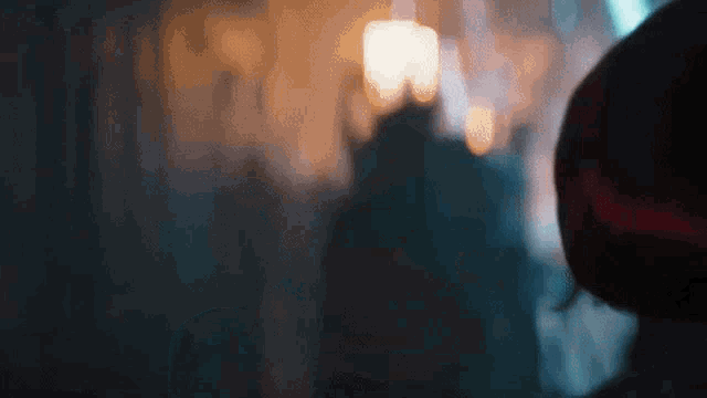a blurry picture of a person standing in a dark room with a candle in the background .