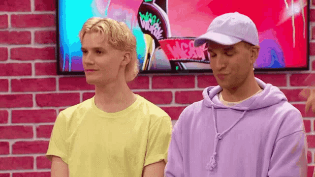 a man wearing a purple hoodie stands next to another man wearing a yellow shirt