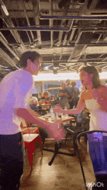 a man and a woman are dancing in a room with tables and chairs
