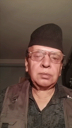 a man wearing glasses and a hat looks at the camera with a blurred background