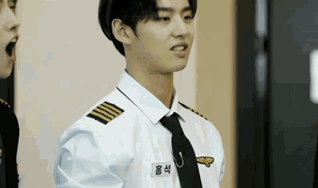 a man in a pilot uniform has a name tag on his chest