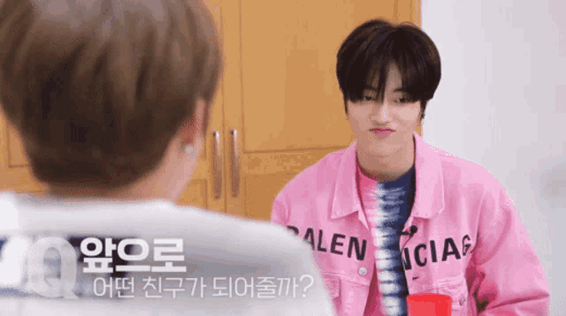 a boy wearing a pink jacket that says balenciag on it
