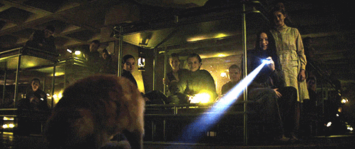 a group of people standing in a dark room with a light coming out of a window