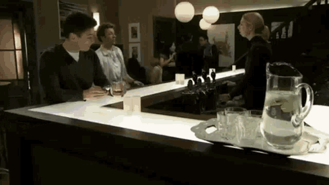 a man is sitting at a bar with a pitcher of water