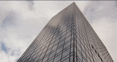 looking up at a tall building with a cloudy sky behind it