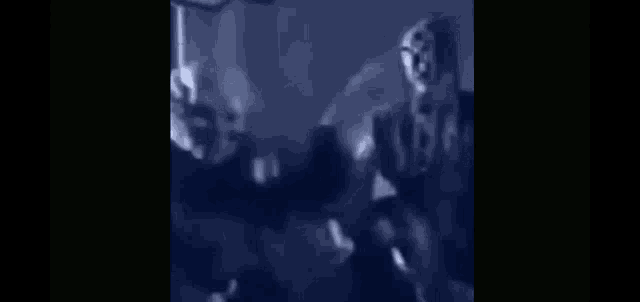 a blurry image of a group of people standing in a dark room .