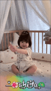 a baby girl is sitting in a crib with the name shenta written on the bottom