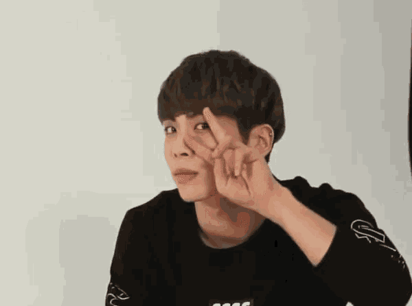 a young man is making a peace sign with his fingers .