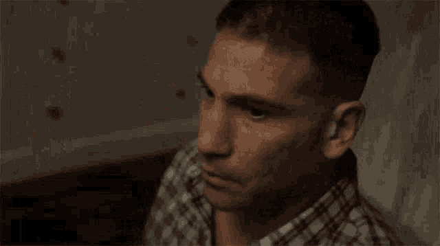 a man in a plaid shirt is crying while holding a hammer .