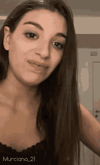 a woman with long hair is looking at the camera while wearing a black top .