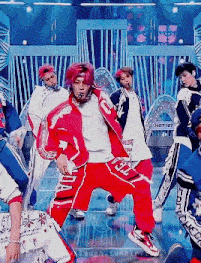 a group of young men are standing on a stage dancing .