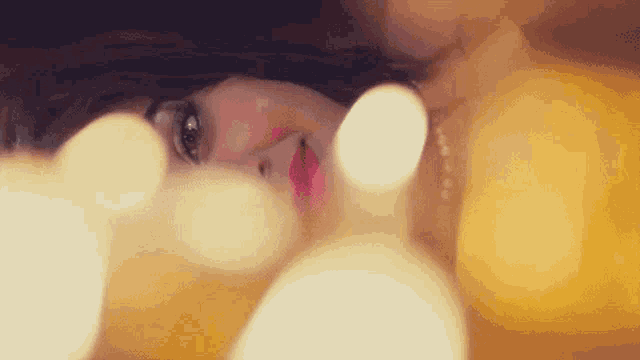a close up of a woman 's face with a blurry background of lights