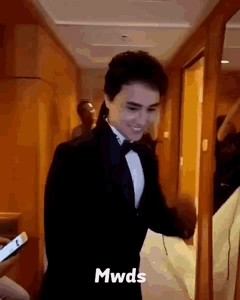 a man in a tuxedo is standing in a hallway with the word mwds on the bottom