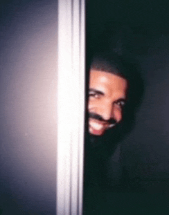 a man with a mustache is peeking out from behind a door and smiling .