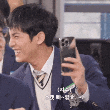 a man in a suit and tie is smiling while holding a cell phone