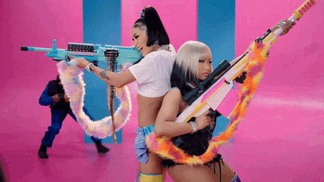 two women holding guns in front of a pink wall