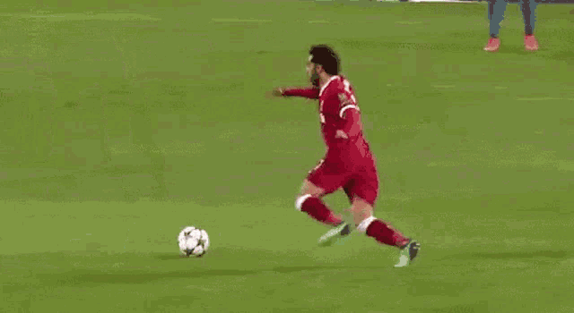 a soccer player wearing a red jersey with the number 11 on it is running on the field .