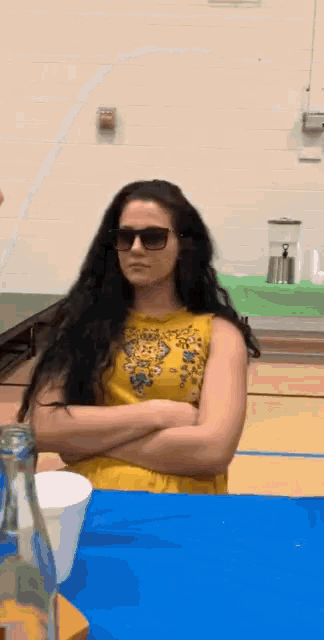 a woman wearing sunglasses and a yellow dress is sitting at a table .