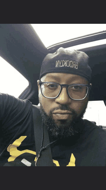 a man wearing glasses and a hat that says brooklyn on it