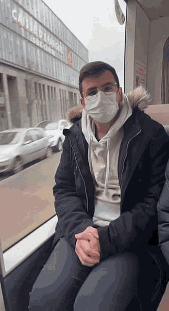a man wearing a mask sits on a bus