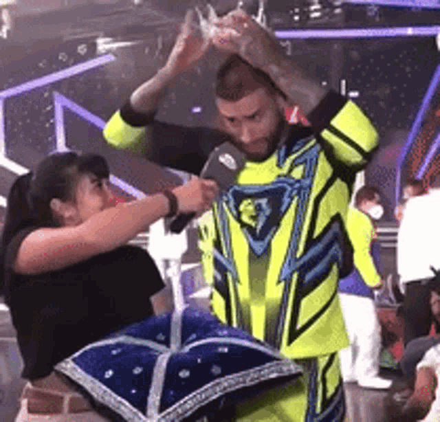 a man in a neon yellow and blue suit is being helped by a woman in a black shirt .