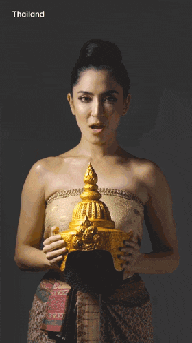 a woman in a gold crop top with thailand written on the bottom