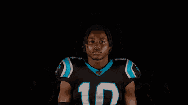 a man wearing a carolina panthers jersey is smiling with the word nah behind him