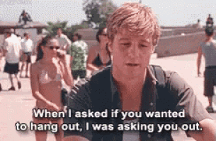 a man in a black shirt is talking to a woman in a bikini .