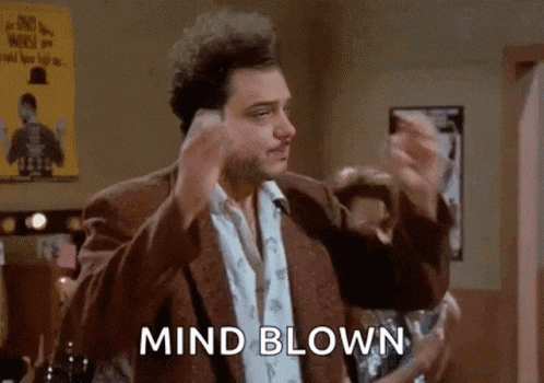 a man in a suit is making a funny face and saying `` mind blown '' in a room .