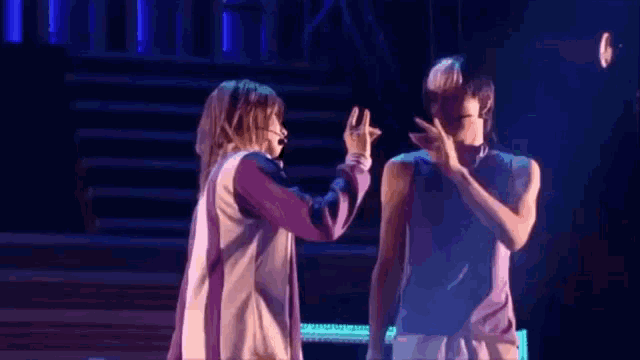 a man and a woman are dancing on a stage and the woman is giving the man a high five .
