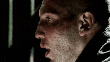 a close up of a man with blood on his face covering his mouth with his hand .
