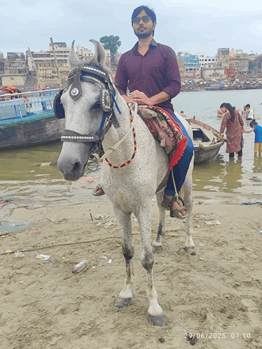 a man riding on the back of a white horse on a beach