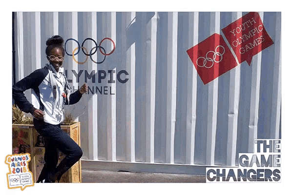a woman stands in front of a wall that says youth olympic games