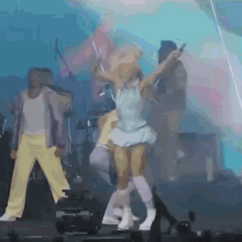 a group of people are dancing on a stage with a microphone .