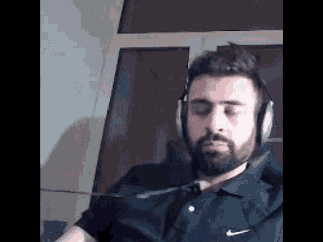 a man with a beard is wearing headphones and a black shirt .