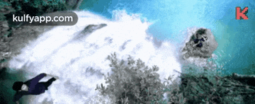 an aerial view of a waterfall with two people swimming in it