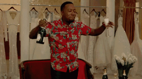 a man in a floral shirt is pouring champagne into a glass .