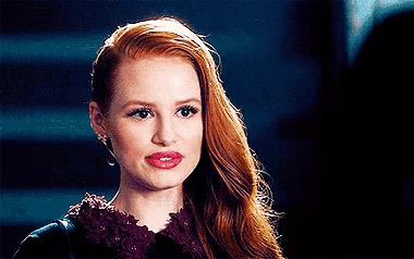 a close up of a woman 's face with red hair and a black jacket .