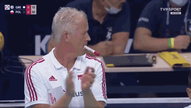 a man wearing an adidas shirt holds a red pen