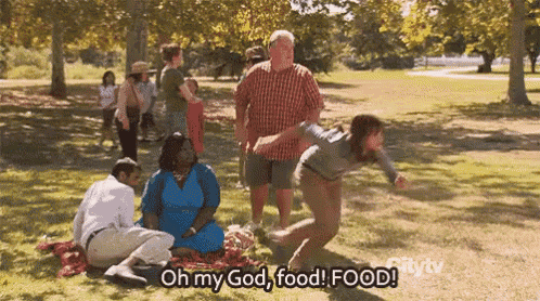 a group of people are having a picnic in a park and one of them is saying " oh my god food food "