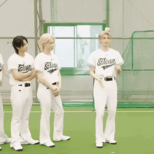 a group of young men wearing baseball uniforms are standing on a baseball field .