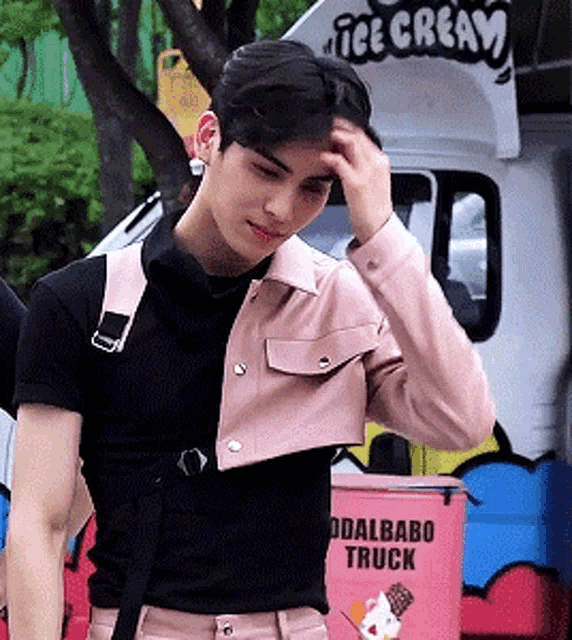 a young man is standing in front of an ice cream truck .