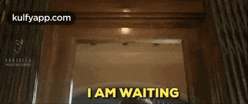 a man is dancing in front of a door with the words i am waiting written on it .