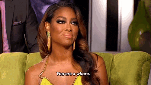 a woman in a yellow dress is sitting on a green couch and saying " you are a whore "