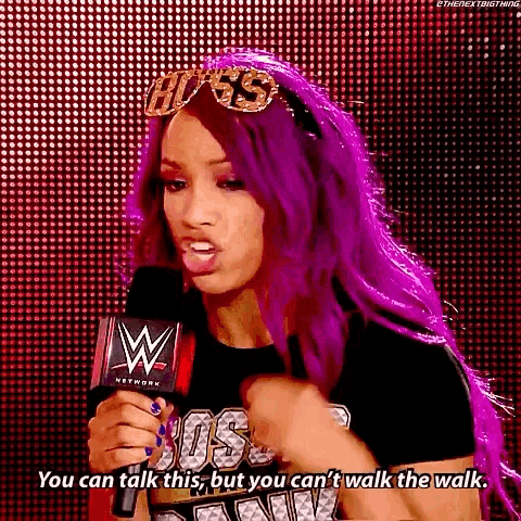 a woman with purple hair is talking into a microphone while wearing a headband .