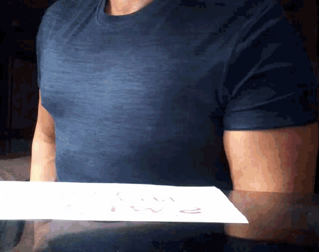 a man in a blue shirt is holding a piece of paper that says " i love you " on it