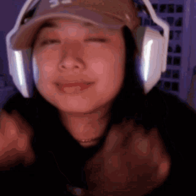 a woman wearing headphones and a hat is smiling and giving a thumbs up .